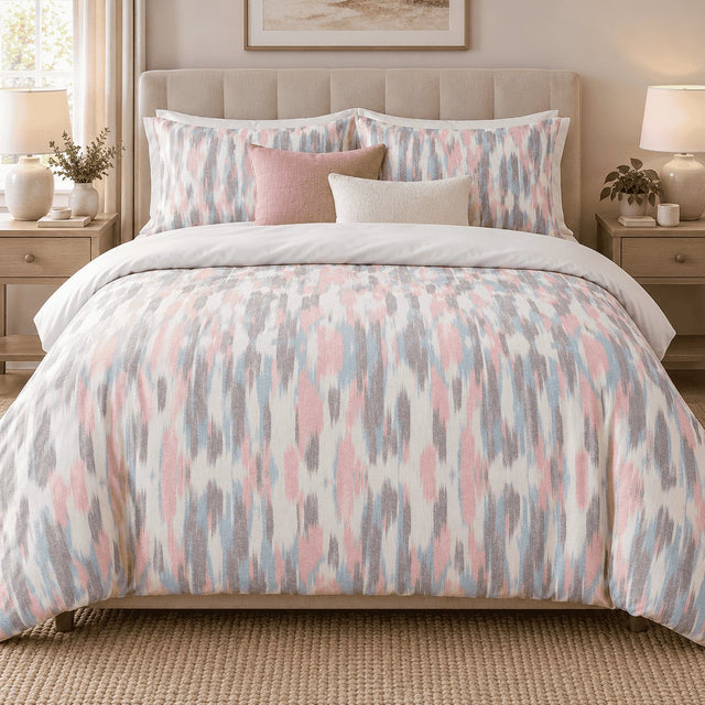 Blush Blue Ikat duvet cover set, front view showing pink, blue and grey ikat streaks on a tufted bed