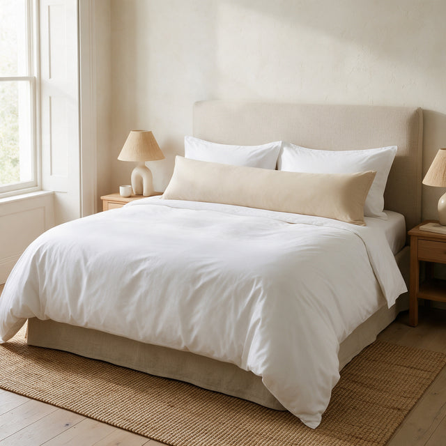 Beige Bolster Pillow with Case lying across the full width of a made king size bed