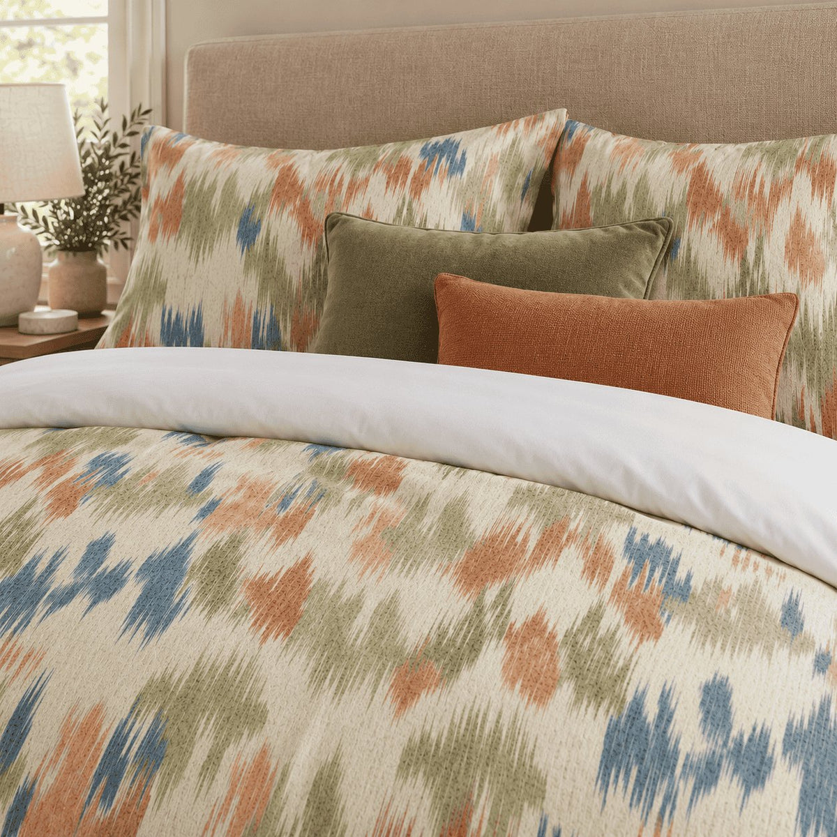 Terracotta Sage Ikat duvet cover set, close-up of ikat pillowcases with olive velvet and rust cushions
